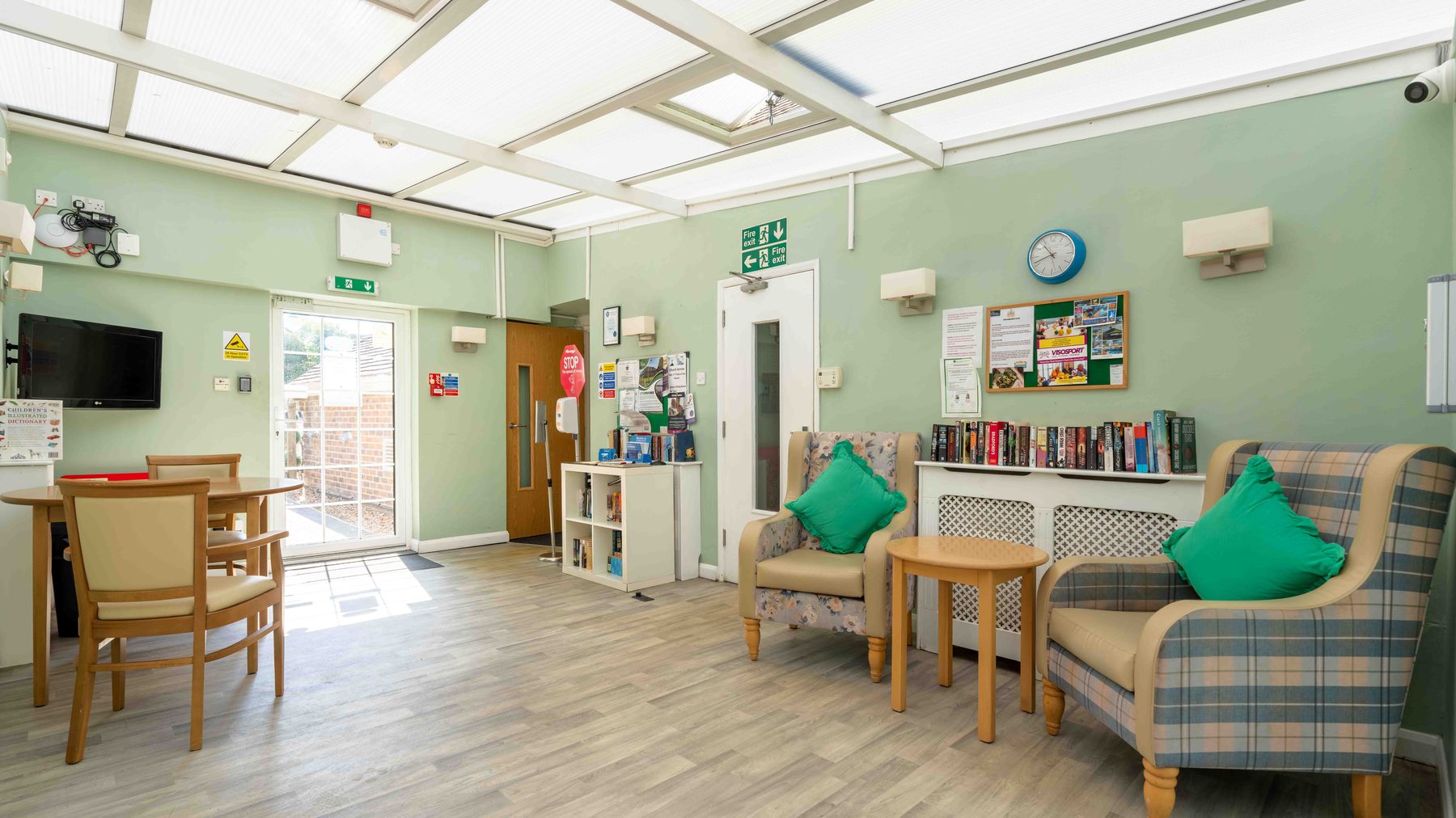 A carer supporting a resident in a comfortable lounge at Little Brook House